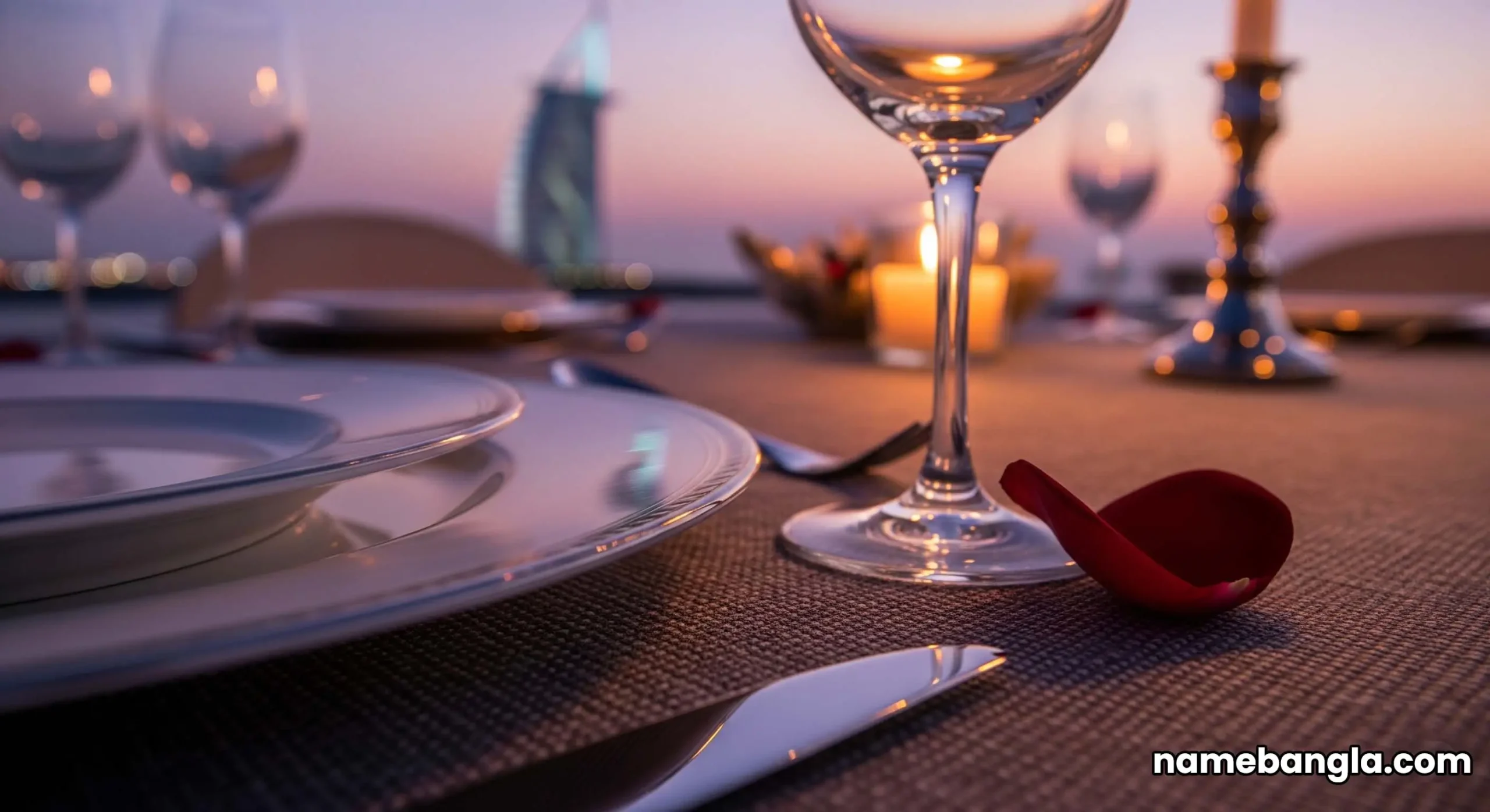 A beautifully set dining table for 20 on the upper deck at dusk. The table is adorned with flowers and fine china, with the iconic silhouette of the Burj Al Arab glowing in the background.