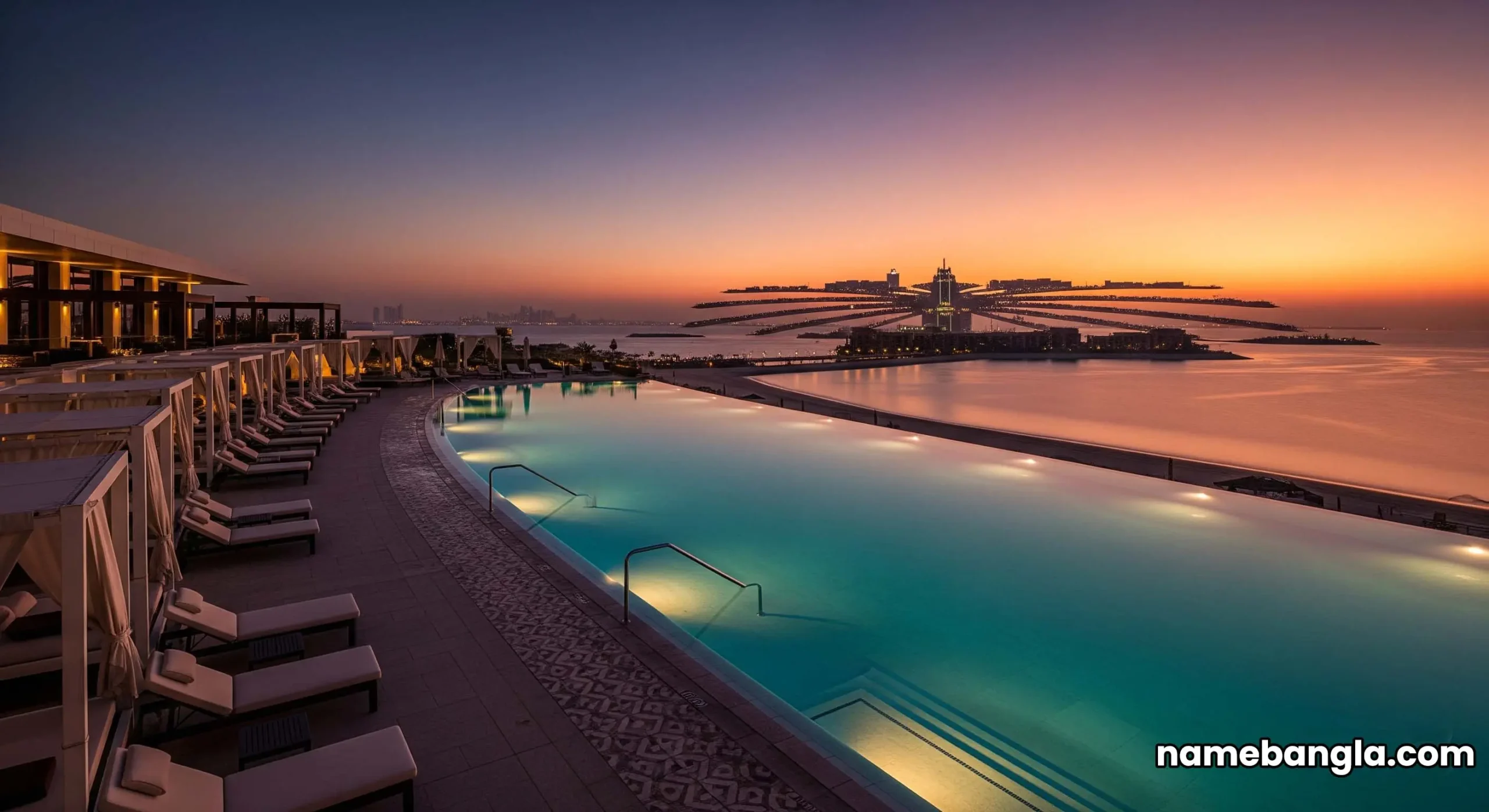A wide-angle shot from a drone perspective, showing the iconic Address Beach Resort infinity pool connecting the two towers, with the sun setting over the Palm Jumeirah in the background.