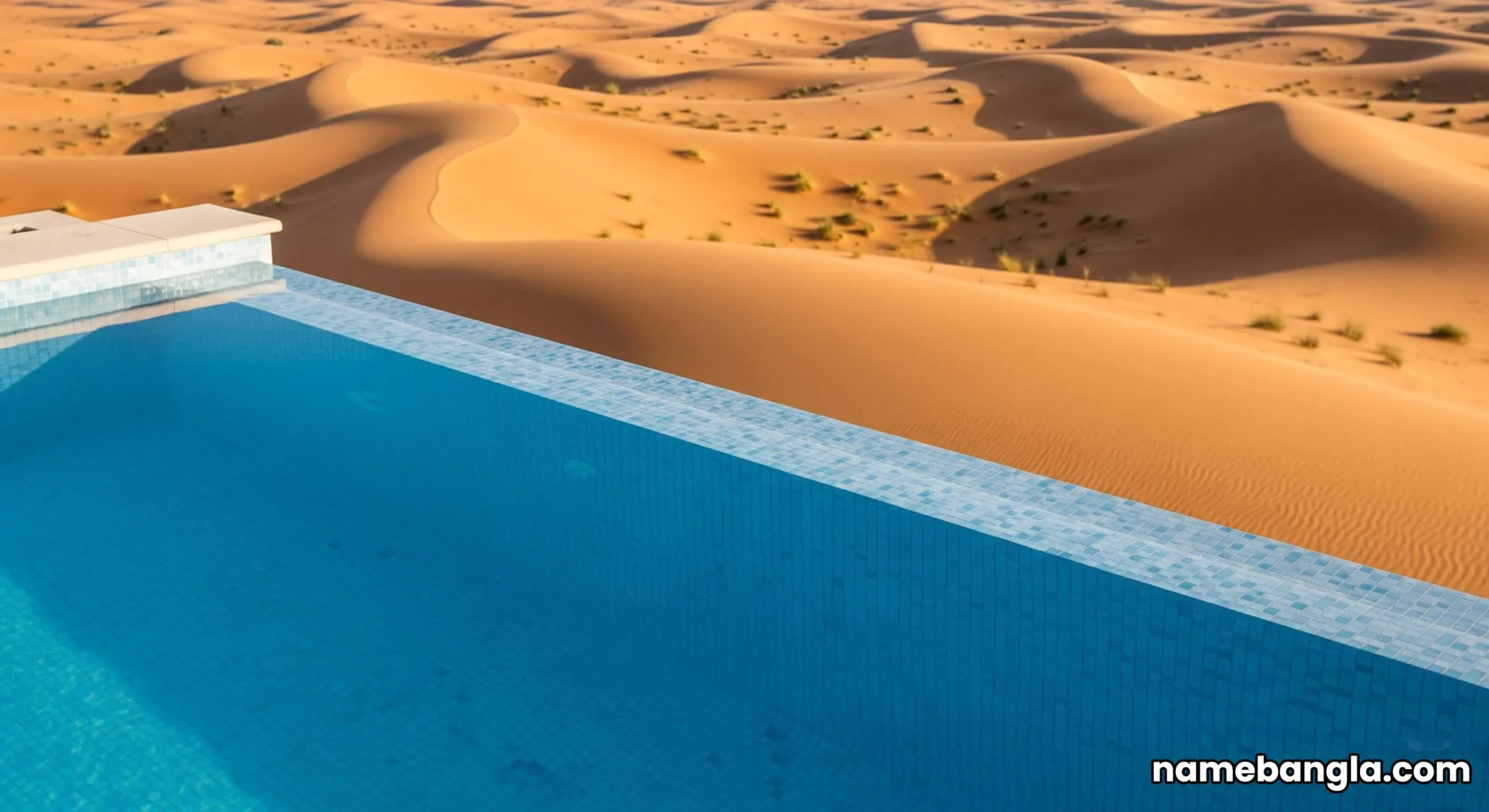 Aerial drone view of a luxury villa and private pool inside The Ritz-Carlton Al Wadi Desert resort, surrounded by vast, golden sand dunes in Ras Al Khaimah.