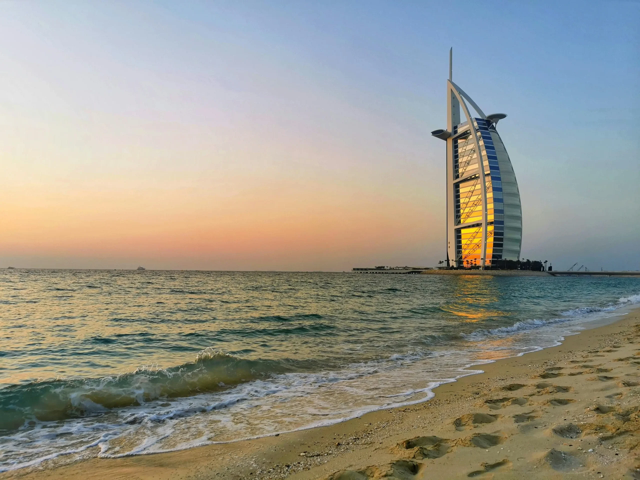 The sail-shaped exterior of the Burj Al Arab hotel in Dubai against a blue sky.