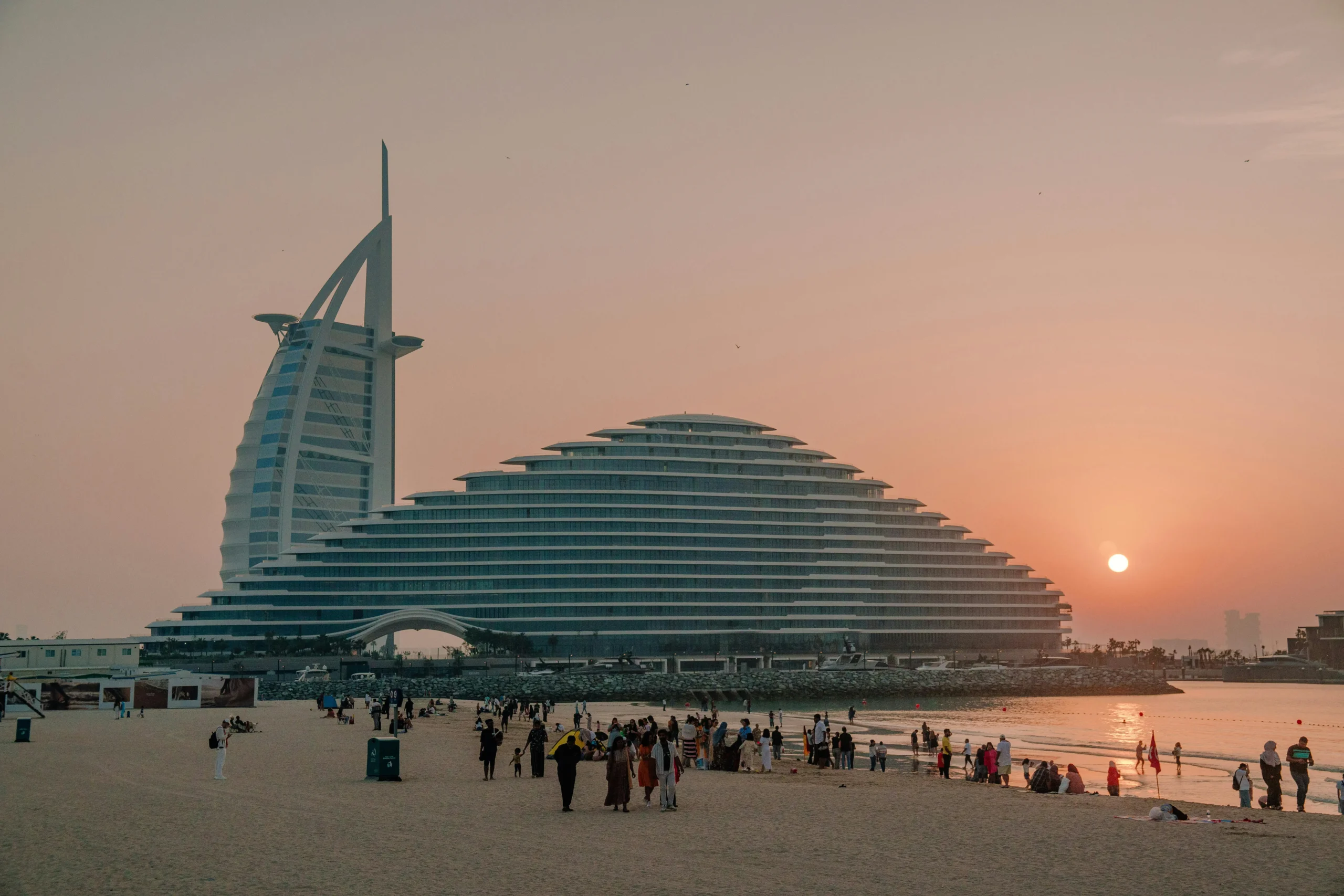 The iconic Burj Al Arab Jumeirah hotel at sunset, glowing against the Dubai coastline.